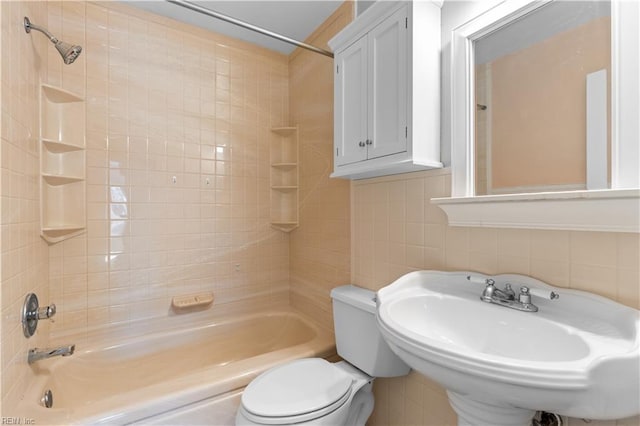 bathroom with toilet, a sink, tile walls, and shower / bathtub combination