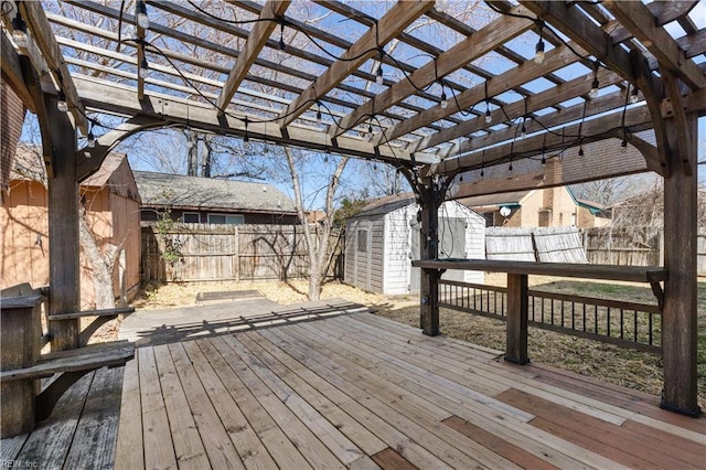 wooden terrace with a storage shed, a fenced backyard, a pergola, and an outbuilding