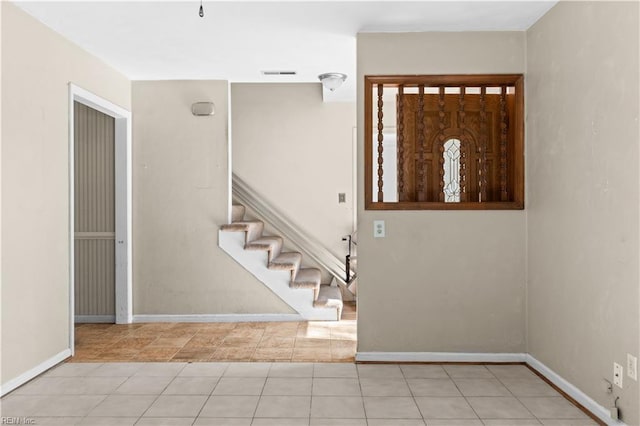 entryway featuring baseboards, stairs, visible vents, and tile patterned floors