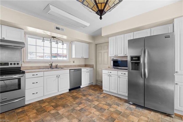 kitchen with under cabinet range hood, a sink, visible vents, light countertops, and appliances with stainless steel finishes