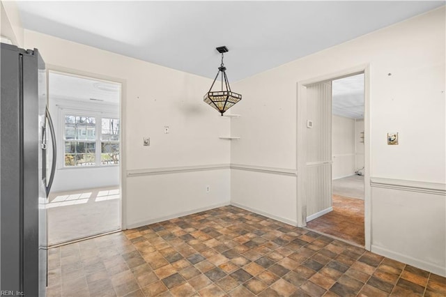 unfurnished dining area with stone finish flooring and baseboards