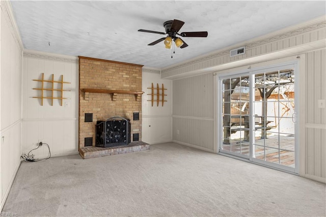 unfurnished living room featuring ceiling fan, a fireplace, visible vents, carpet, and crown molding