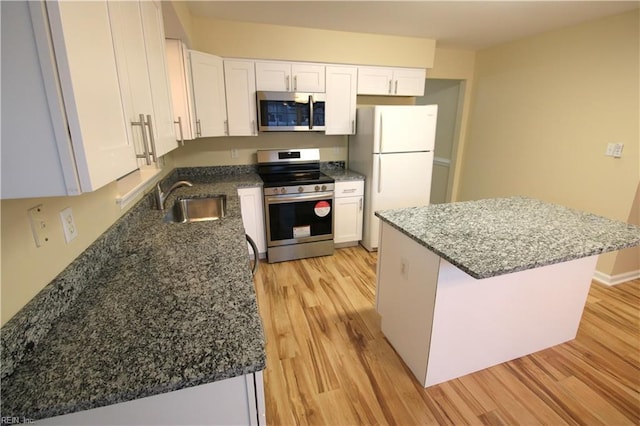 kitchen featuring appliances with stainless steel finishes, white cabinetry, a sink, and light wood-style flooring