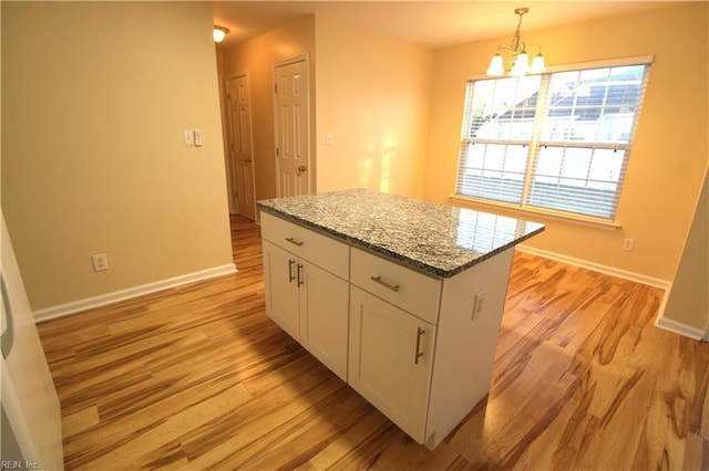 kitchen featuring a chandelier, white cabinets, hanging light fixtures, light wood-type flooring, and a center island