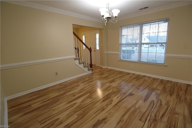 spare room featuring wood finished floors, visible vents, stairs, an inviting chandelier, and crown molding