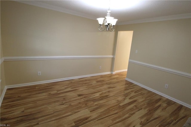 unfurnished room with a chandelier, ornamental molding, wood finished floors, and baseboards