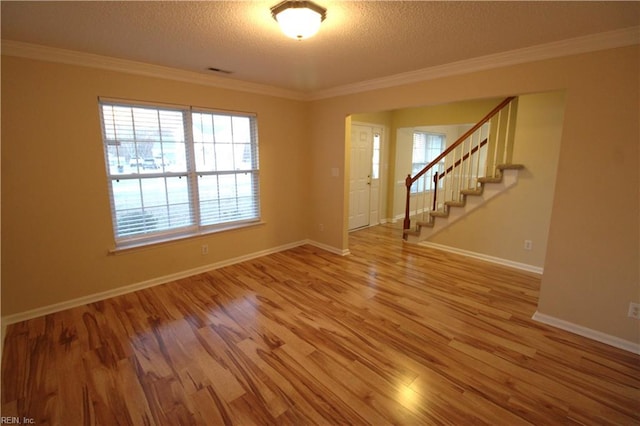 spare room with stairs, crown molding, a textured ceiling, and wood finished floors