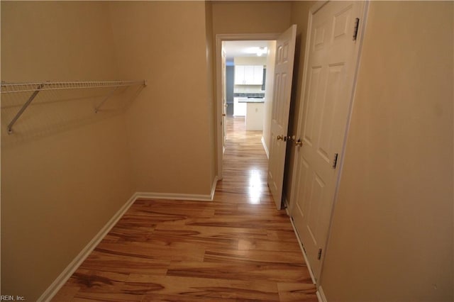 hall with light wood-type flooring and baseboards