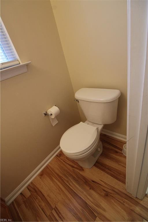 bathroom with wood finished floors, toilet, and baseboards