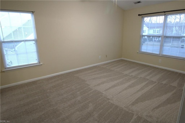 empty room featuring light colored carpet, visible vents, and baseboards