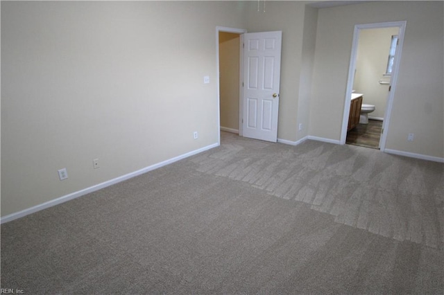 unfurnished bedroom with carpet floors, ensuite bath, and baseboards