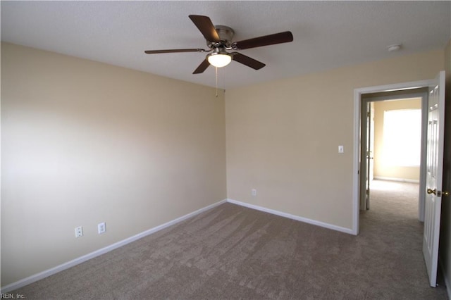 carpeted spare room with ceiling fan and baseboards