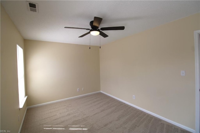 carpeted spare room with a textured ceiling, ceiling fan, visible vents, and baseboards