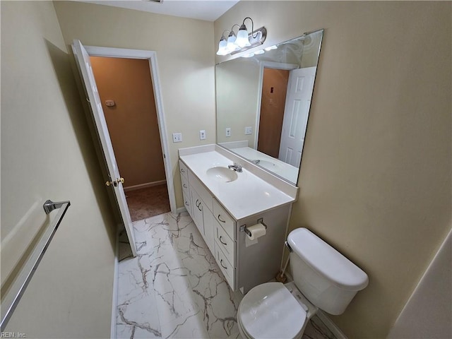 bathroom featuring toilet, marble finish floor, baseboards, and vanity