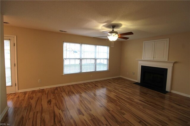 unfurnished living room with baseboards, visible vents, a fireplace with flush hearth, wood finished floors, and a textured ceiling