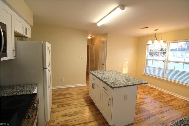 kitchen with light stone counters, white cabinetry, a center island, stainless steel electric range oven, and light wood finished floors