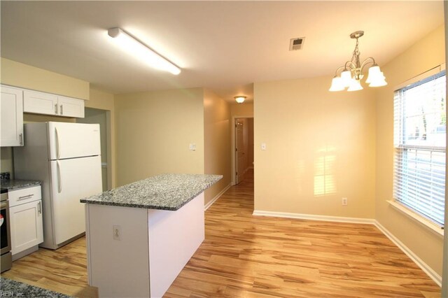 kitchen featuring a kitchen island, visible vents, light wood-style floors, white cabinetry, and freestanding refrigerator