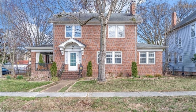 view of front of property featuring brick siding, a chimney, a front lawn, and fence