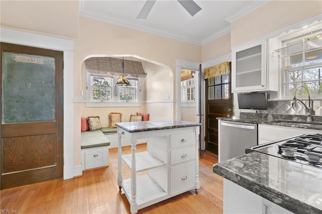 kitchen with a sink, white cabinets, light wood-style floors, dishwasher, and crown molding