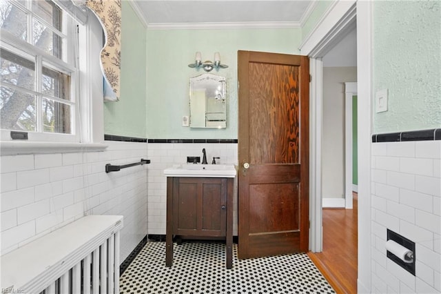 bathroom featuring wainscoting, vanity, tile walls, and crown molding