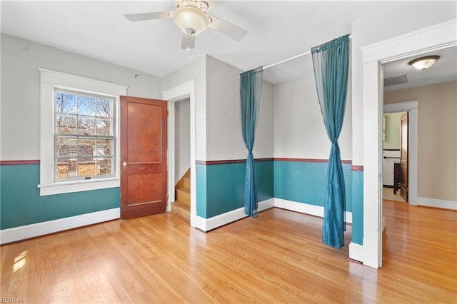 spare room featuring ceiling fan, stairs, baseboards, and wood finished floors