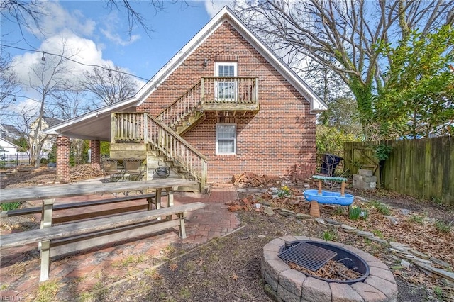 back of house with brick siding, a fire pit, fence, stairs, and a patio area