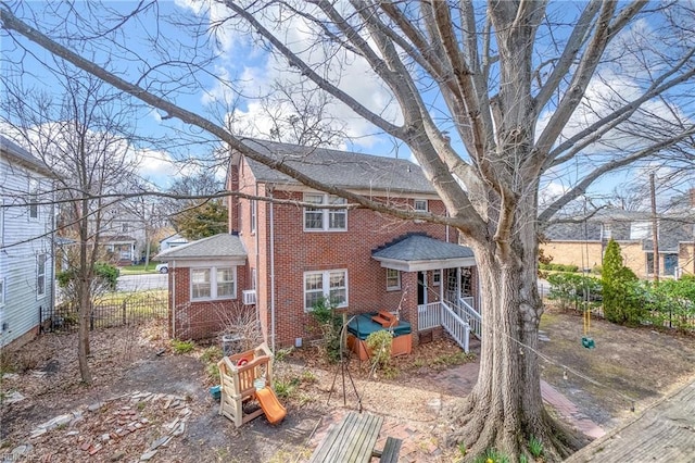 view of front of house featuring brick siding and fence