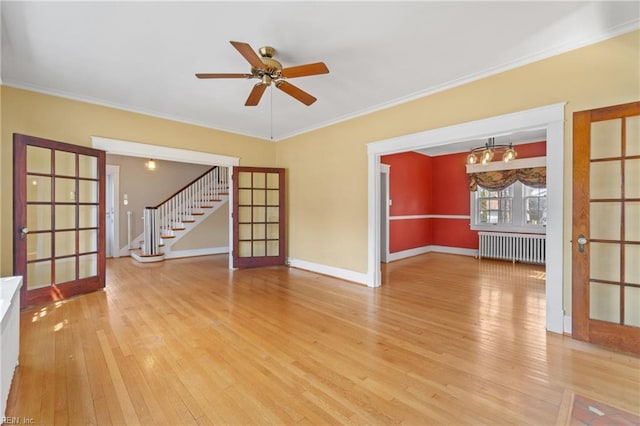 unfurnished room featuring french doors, radiator, light wood-style flooring, and stairs