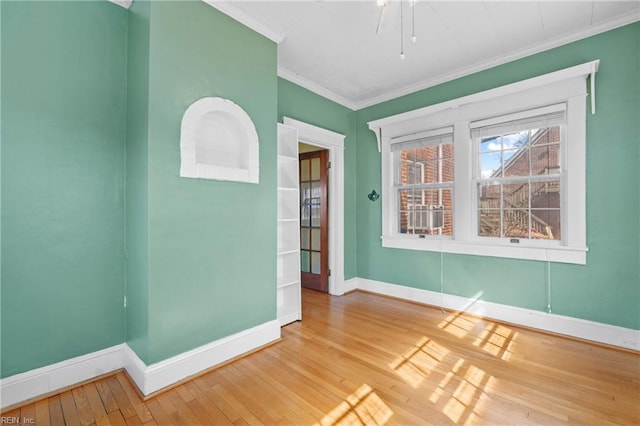 empty room with crown molding, baseboards, and wood-type flooring