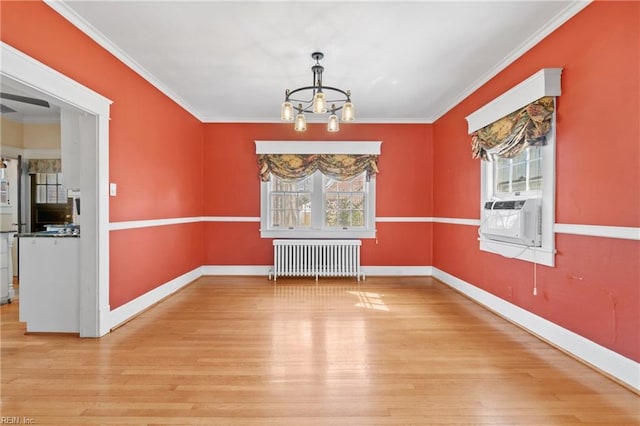 unfurnished dining area featuring wood finished floors, radiator heating unit, cooling unit, an inviting chandelier, and crown molding