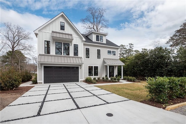 modern farmhouse style home with concrete driveway, metal roof, an attached garage, a standing seam roof, and board and batten siding