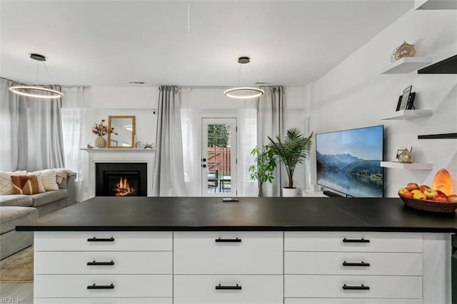 kitchen featuring open shelves, a warm lit fireplace, white cabinetry, dark countertops, and open floor plan