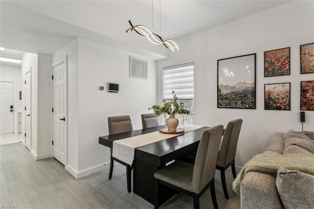 dining room featuring visible vents, light wood-style flooring, and baseboards