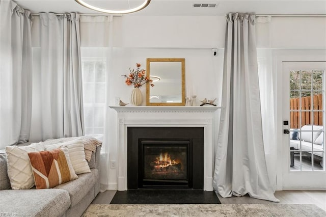 sitting room with a fireplace with flush hearth and visible vents