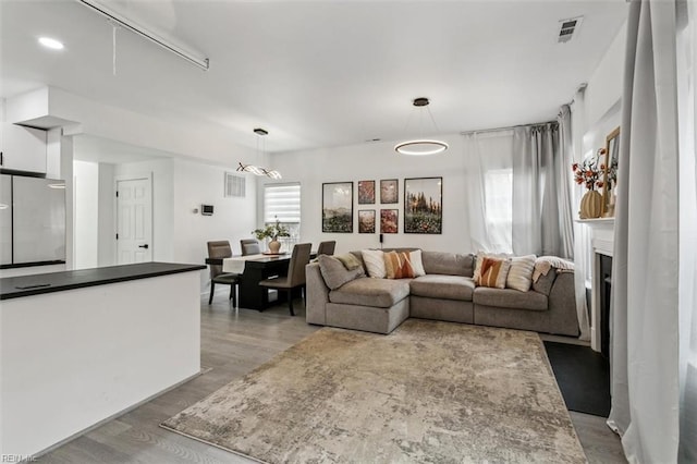 living room featuring light wood finished floors, visible vents, and a fireplace