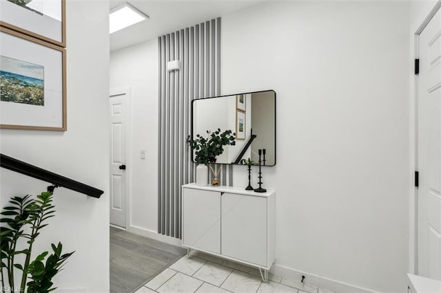 hallway featuring marble finish floor and baseboards