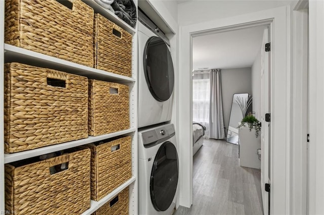 clothes washing area featuring laundry area, stacked washing maching and dryer, and wood finished floors