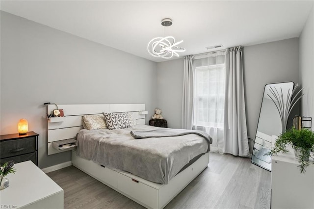 bedroom with visible vents, baseboards, light wood-style floors, and a chandelier