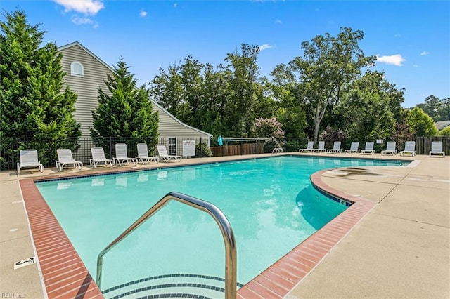 community pool with a patio area and fence