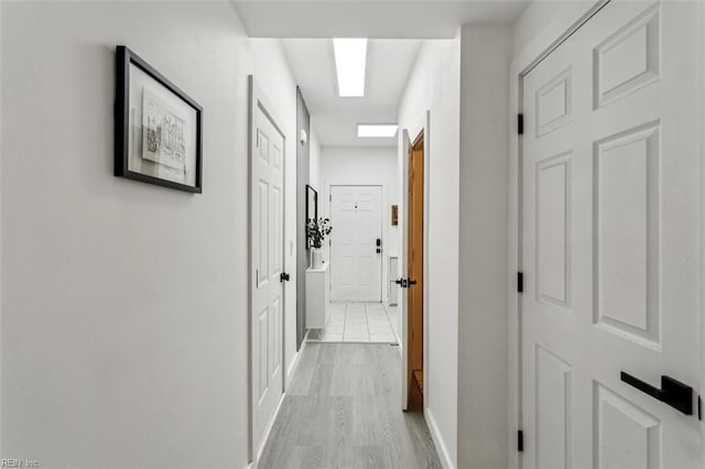 corridor with light wood-type flooring and baseboards