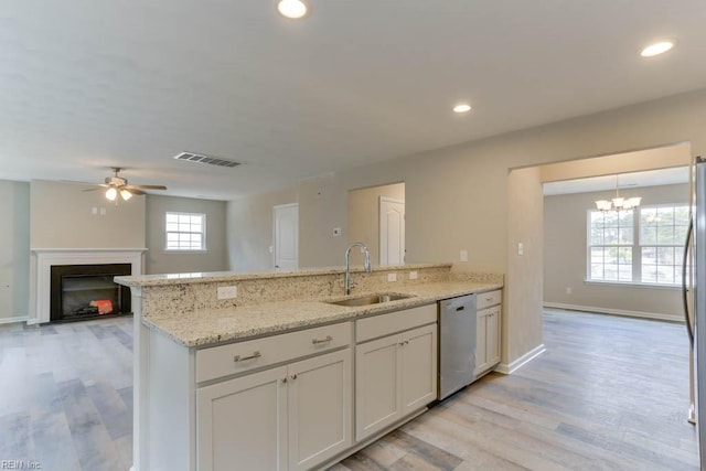 kitchen with dishwashing machine, a peninsula, a fireplace, a sink, and visible vents