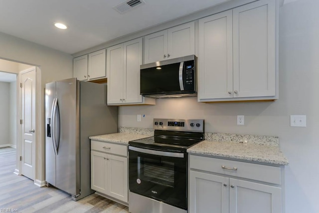 kitchen with light stone counters, recessed lighting, visible vents, appliances with stainless steel finishes, and light wood-style floors