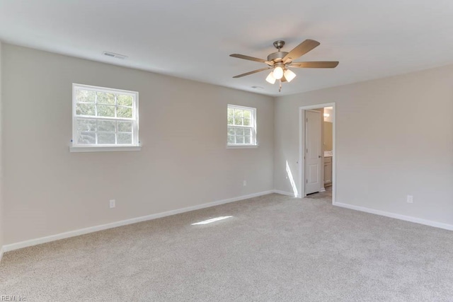 unfurnished room with baseboards, ceiling fan, visible vents, and light colored carpet