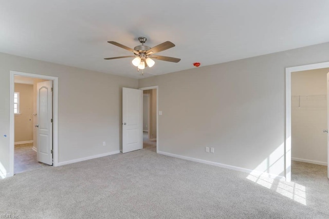 unfurnished bedroom featuring light carpet, a spacious closet, a closet, and baseboards