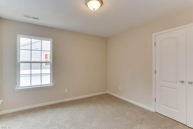 unfurnished room featuring light colored carpet, visible vents, and baseboards