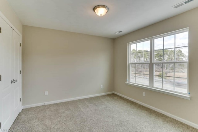 unfurnished room with light carpet, visible vents, and baseboards