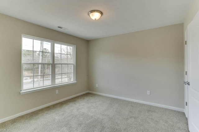 carpeted spare room with visible vents and baseboards