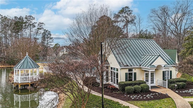 view of side of home with french doors, metal roof, a standing seam roof, and a water view