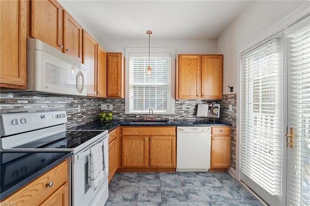 kitchen featuring dark countertops, hanging light fixtures, decorative backsplash, a sink, and white appliances