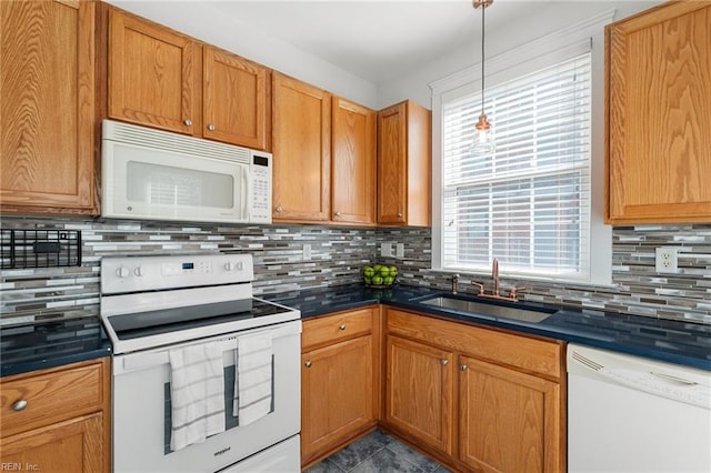 kitchen featuring dark countertops, white appliances, tasteful backsplash, and a sink